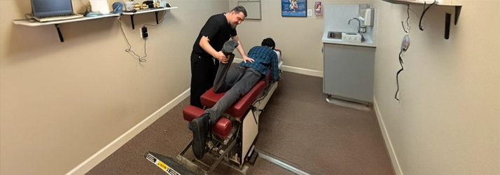 Dr. Brian Long performing a lower‑back adjustment using a specialized treatment table.