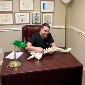 Dr. Brian Long reviewing a spine model while explaining structural alignment and treatment.